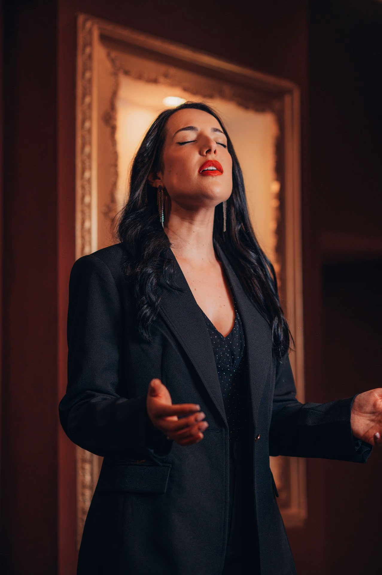 Cantante de Fado morena, de americana negra, con los ojos cerrados y una mano tendida mientras canta, en la sala de la Baixa de Lisboa