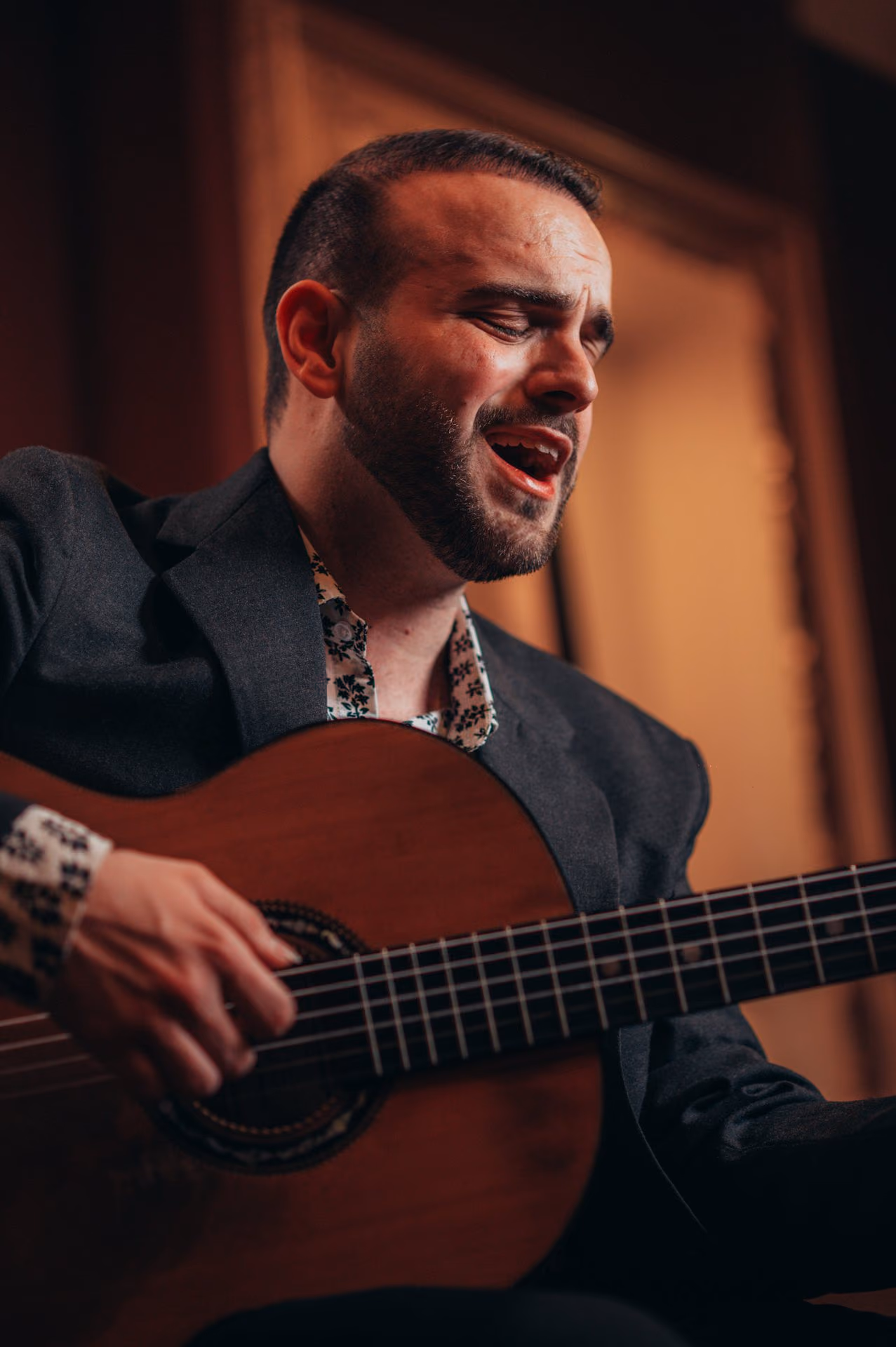 Con la guitarra clásica en las manos y los ojos cerrados, un músico canta Fado ante un marco dorado de la sala de la Baixa, en Lisboa