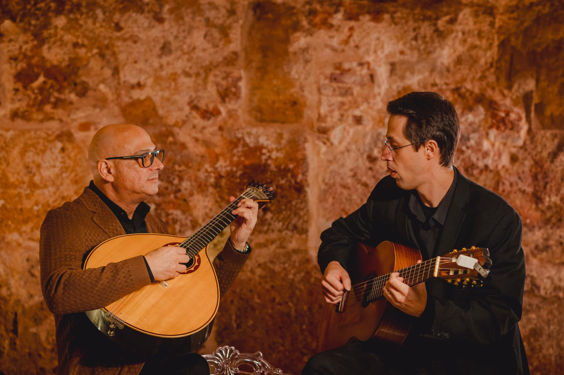 La guitarra portuguesa y la guitarra clásica frente a frente en un concierto de Fado: los dos guitarristas se miran en la sala de la Sé de Lisboa
